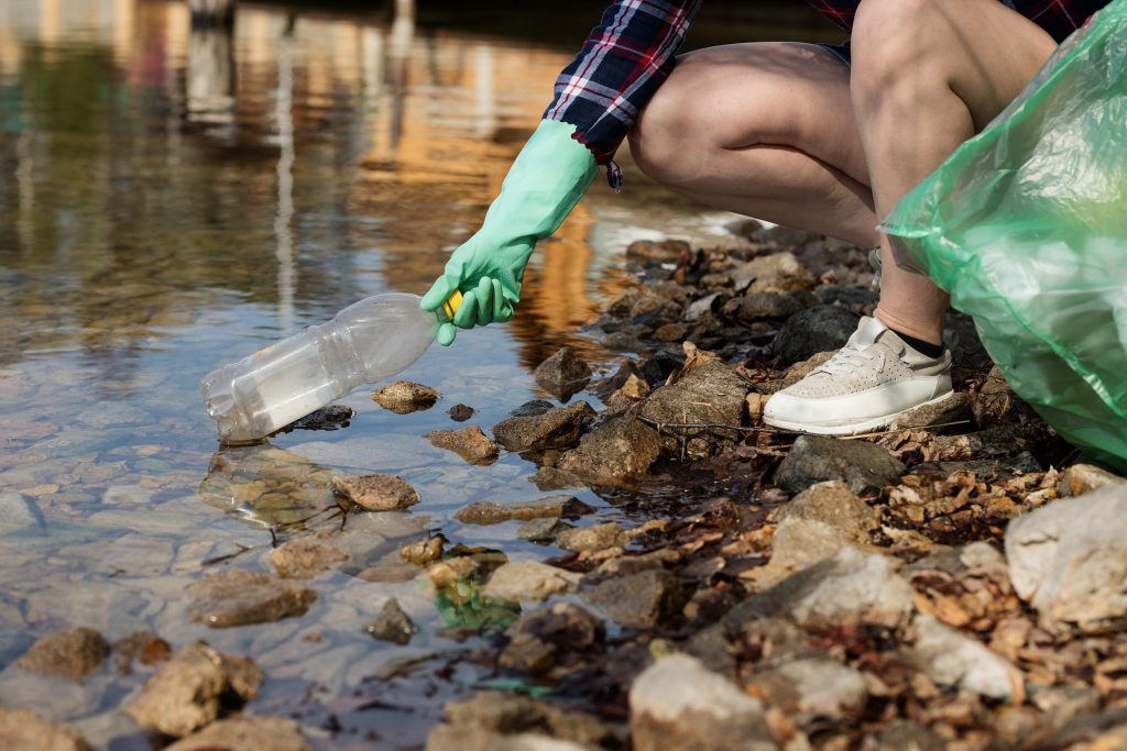 En person plockar upp plastskräp från naturen.